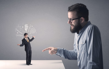 Young businessman fighting with miniature businessman