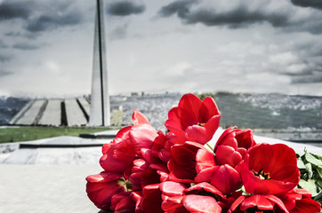 Red tulips in Tsitsernakaberd with Armenian genocide memorial on background.
