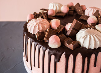 Biscuit cake with chocolate drips, marshmallows and marmalade, slice of chocolate. Sweets and food