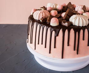 Biscuit cake with chocolate drips, marshmallows and marmalade, slice of chocolate. Sweets and food