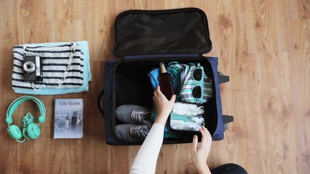 hands packing travel bag with personal stuff