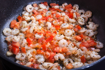 peeled shrimp fried in a pan with tomatoes.closeup