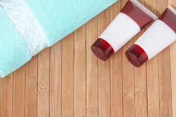 Spa and beauty motif wallpaper. Bathroom accessories wallpaper. Tubes with body lotion and cream and bath towel on straw mat 