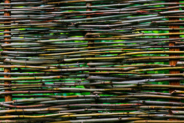texture of woven vines,Detail of a new wicker fence no nails,wicker rustic fence in the summer garden on grass background,fence of woven willow twigs © bondvit