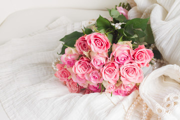 Female dress and jewellery with freah roses bouquet on chair