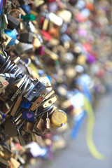 Many hanging locks of different shapes, fastened to each other, hanging on the bridge