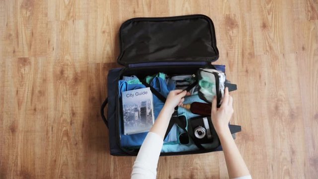 hands packing travel bag with personal stuff