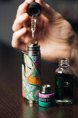 Man in a vape shop is filling a special liquid in e-cigarette.