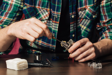 Man repairing e-evaporator,Maintenance of electronic mech mod vaping device.Modern vaporizer e-cig...