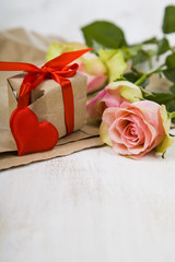 Pink roses,  gift and hearts on a wooden background.