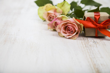 Pink roses and gift  on a wooden background.