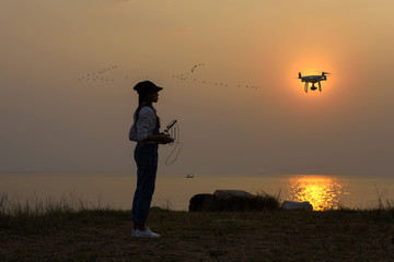 drone flying practice by girl on beach at sunset silhouette
