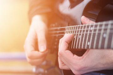 Close up of male guitarist playing electric guitar. Lens flare