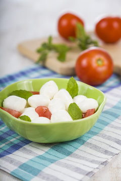 Mozzarella in a green plate on a wooden table. Mozzarella balls