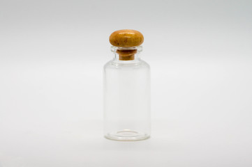 Smal clear glass bottle with wooden cab, isolated on white background.