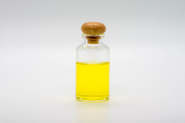 Smal clear glass bottle with wooden cab and yellow liquid, isolated on white background.
