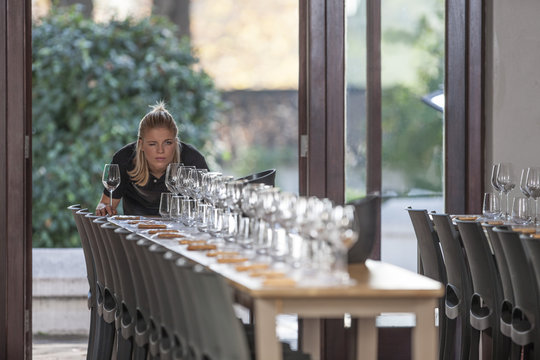 Waitress lining up row of wine glasses at restaurant