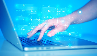 Hand pressing keyboard with high tech media icons