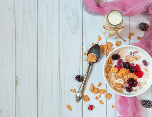 Muesli and berries in a bowl. Bottle with milk. Top view