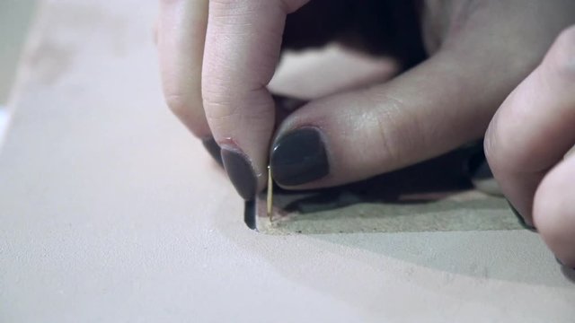 Hand of designer inserts a the nail in the photo frame in a creative workshop. Slow motion.