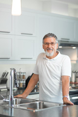 Senior man standing in his renovated, modern kitchen,