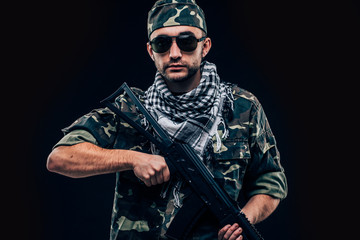 Portrait of a heavily armed masked soldier with black background concept