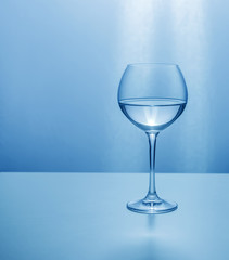 Glass transparent glass half-filled with liquid in blue colors