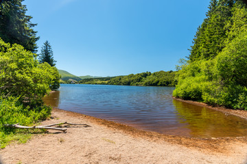 Vue sur le lac de Guery en Auvergne. Plage au bord du lac et ciel bleu.