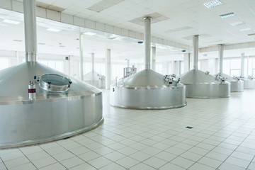 Brewing production - metal beer tanksin a spacious hall. Brewery.