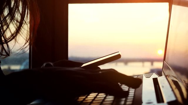 Online mobile payment method using mobile smart phone and credit card. Woman shopping with her laptop on blurred city background during amazing sunset. 3840x2160