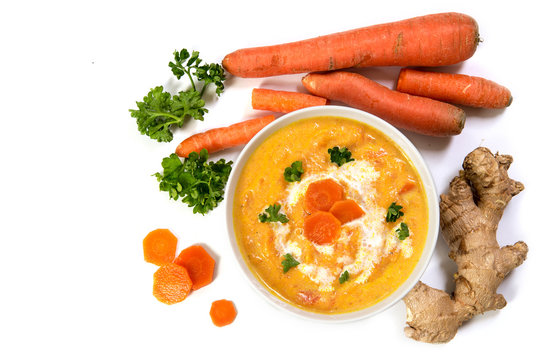 Carrot cream soup with ingedients, ginger root, raw carots and parsley, from above, isolated  on white