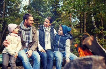 happy family sitting on bench at camp fire