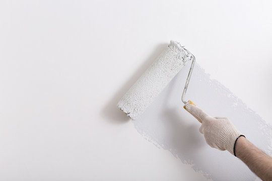 Close up of painter arm painting a wall in gray with paint roller
