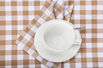 top view of a teacup and saucer on a checkered tablecloth