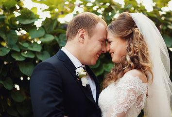 Happy beautiful newlyweds posing outside