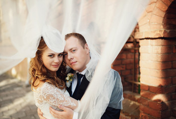 Happy beautiful newlyweds posing on the old street