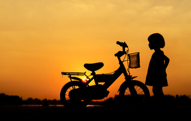 Fototapeta na wymiar Little girl riding bike, Asian kid ,Silhouette a kid at the suns