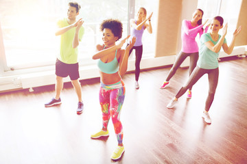 group of smiling people dancing in gym or studio