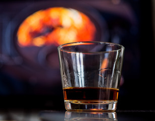 glass of rum before fireplace on mountains