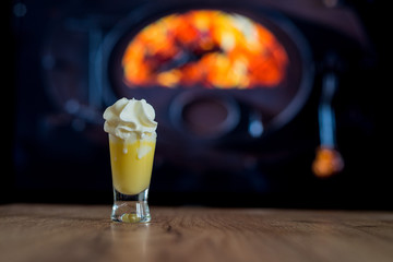 egg nog with whipped cream before fireplace on mountains