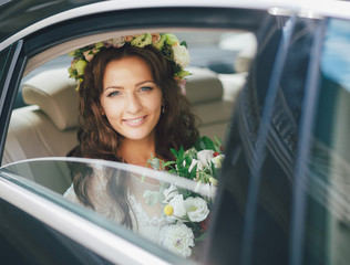 Charming bride with the wreath inside the car