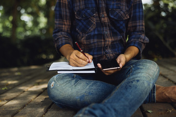 hand using mobile smart phone and writing on notebook