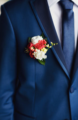 Colorful boutonniere on the blue suit of the groom