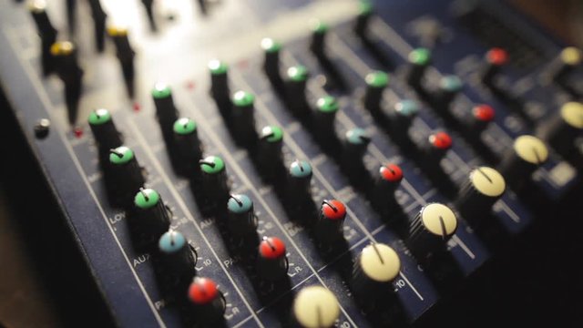 Close up video of a mixer desk with many buttons and shifting focus.