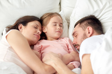 happy family sleeping in bed at home
