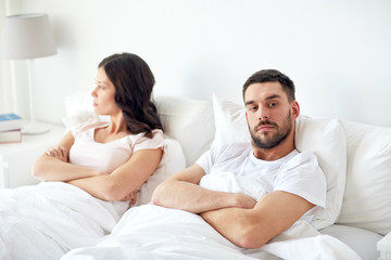 unhappy couple having conflict in bed at home