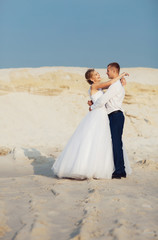 Fototapeta na wymiar Joyful hug of the newlyweds in the desert