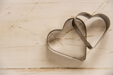 Metal molds for baking in the form of hearts on the wooden backg