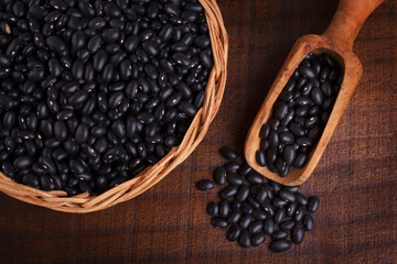 Black beans in scoop on wooden background