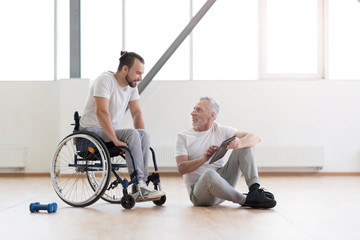 Obraz premium Cheerful orthopedist communicating with disabled patient in the gym